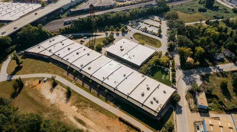 Aerial view of low-slope commercial building roofs surrounded by trees