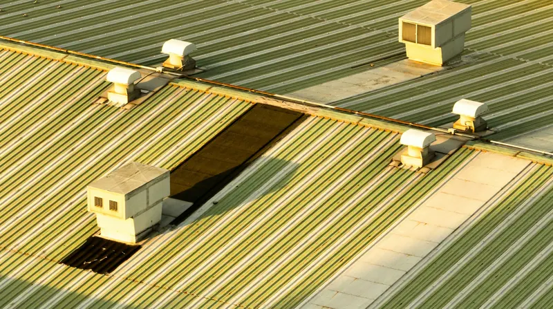 Commercial metal roof with rooftop ventilation units and an open panel section
