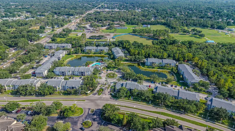 Aerial view of a Florida condominium community with three-story buildings, ponds and a pool